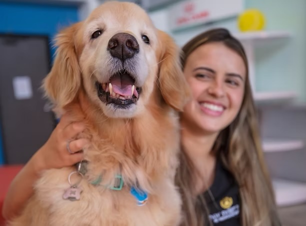 Happy golden retriever smiling alongside a veterinary team member, representing senior pet care services in Irvine